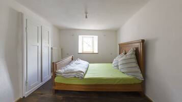 A small, narrow room with a single bed, a radiator, and a window.
