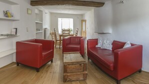 A living room with red leather sofas, a wooden coffee table, and a wooden dining table with chairs. - Nengshof - Haus Gänseblümchen (Wissmannsdorf)