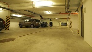 A parking garage with multiple cars parked, concrete floors, and industrial-style lighting. - Hotel B&B Wrocław Centrum (Wroclaw)