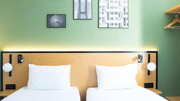 A hotel room with two beds, a wooden headboard, and wall-mounted artwork.