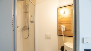 A compact bathroom with a glass-enclosed shower, a toilet, and a hairdryer mounted on the wall. - Hotel B&B Wrocław Centrum (Wroclaw)
