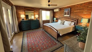 A bedroom with a brick wall, a bed, a dresser, and a ceiling fan. - Tucson Gem in the Heart of the Desert (Tucson)