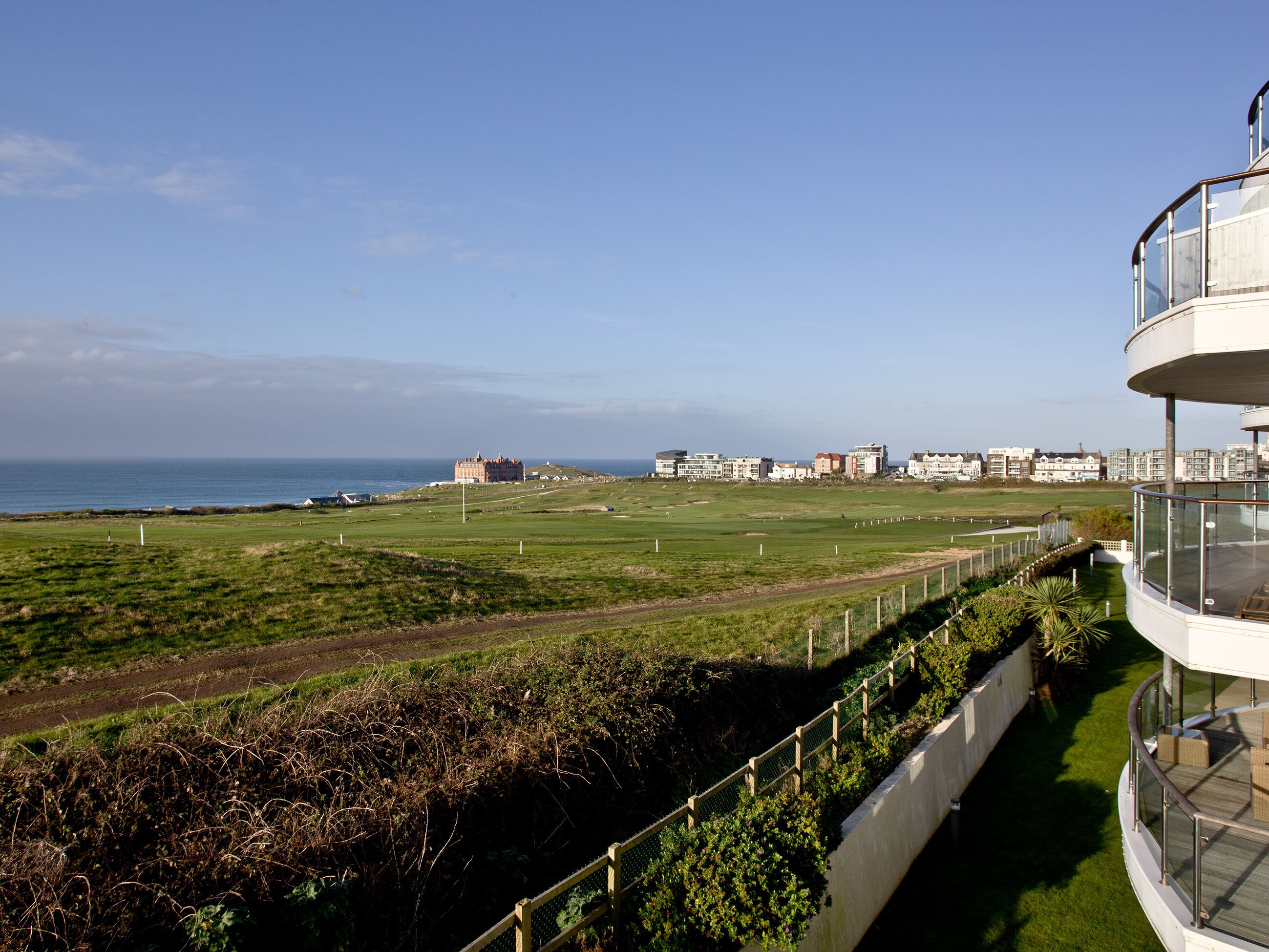 A coastal view with a golf course, a historic building, and modern residential buildings.