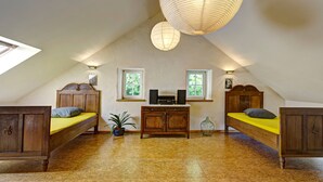 A bedroom with two wooden beds, a small table with speakers, and a large hanging light fixture. - Nengshof - Haus Königskerze (Wissmannsdorf)