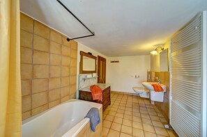 Ein Badezimmer mit Badewanne, Waschbecken, Toilette und einem Waschtisch mit Spiegel.