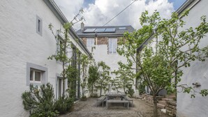 A courtyard with a stone bench, a small table, and a tree. - Nengshof - Haus Königskerze (Wissmannsdorf)