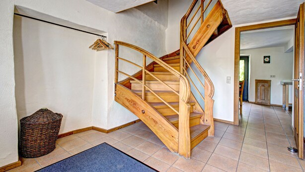 A wooden staircase with a handrail, a basket, and a blue mat on the floor. - Nengshof - Haus Königskerze (Wissmannsdorf)