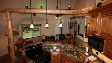 Une cuisine avec des meubles en bois, un plan de travail en granit, une cuisinière et des luminaires suspendus.