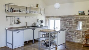 A compact kitchen with a dishwasher, a coffee maker, and a stone fireplace. - Nengshof - Haus Wildrose (Wissmannsdorf)