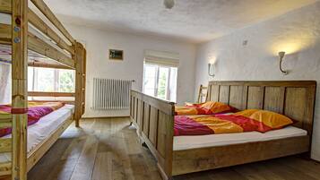 A room with bunk beds, a radiator, a window with blinds, and a wall-mounted light fixture.