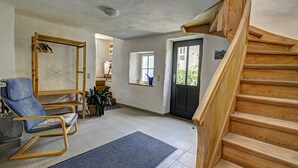 A spacious living area with a wooden staircase, a blue chair, and a window with a view. - Nengshof - Haus Ehrenpreis (Wissmannsdorf)