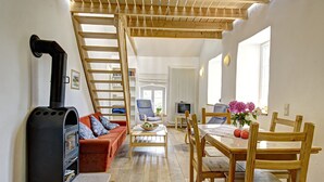 A cozy living room with a fireplace, a sofa, a dining table with chairs, and a TV. - Nengshof - Haus Ehrenpreis (Wissmannsdorf)