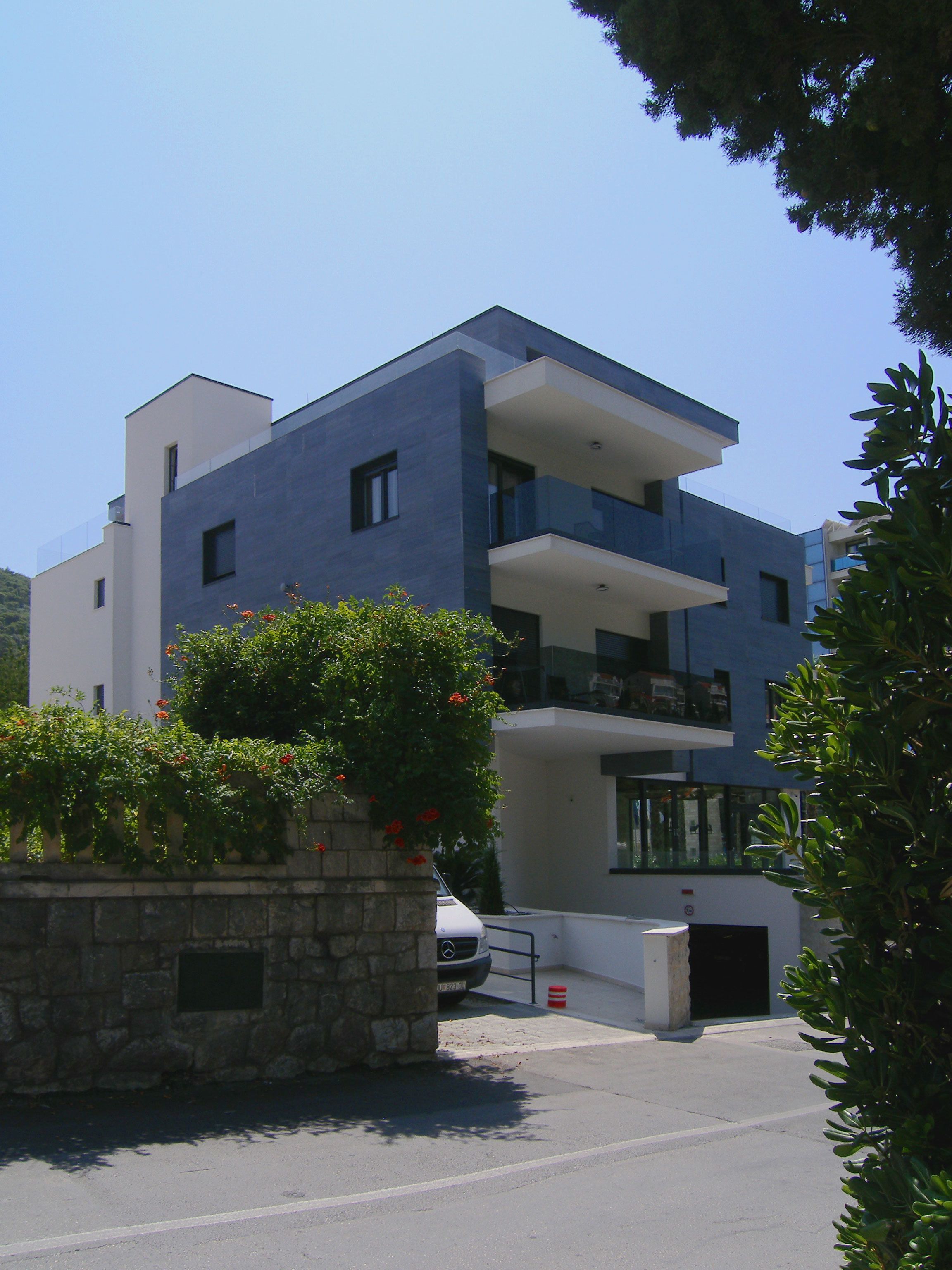 Ein modernes, zweistöckiges Gebäude mit flachem Dach, großen Fenstern und einem Balkon.