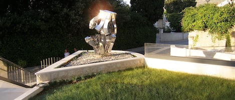 Una escultura moderna en una zona verda amb un camí de pedra i gespa.