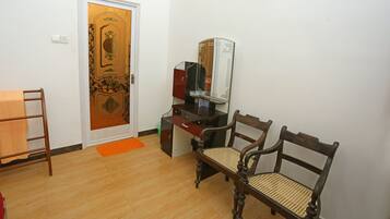 Une pièce avec un plancher en bois, un bureau doté d’un miroir, une chaise et une porte ornée d’un motif décoratif.