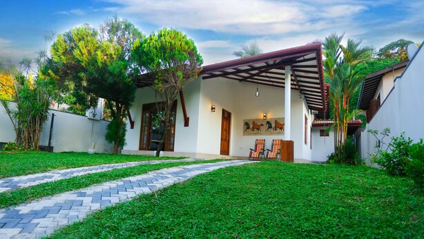 Une maison moderne avec une allée pavée, un patio couvert et une pelouse bien entretenue.
