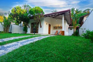 A modern house with a paved driveway, a covered patio, and a well-maintained lawn. - Villa 26 (Galle)