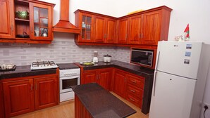 Une cuisine équipée de meubles de rangement en bois, d’une cuisinière, d’un four, d’un four à micro-ondes et d’un réfrigérateur.