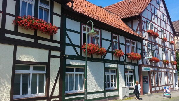 Un bâtiment traditionnel à colombages, agrémenté de jardinières aux fenêtres et d’une enseigne indiquant qu’il s’agit d’un restaurant.