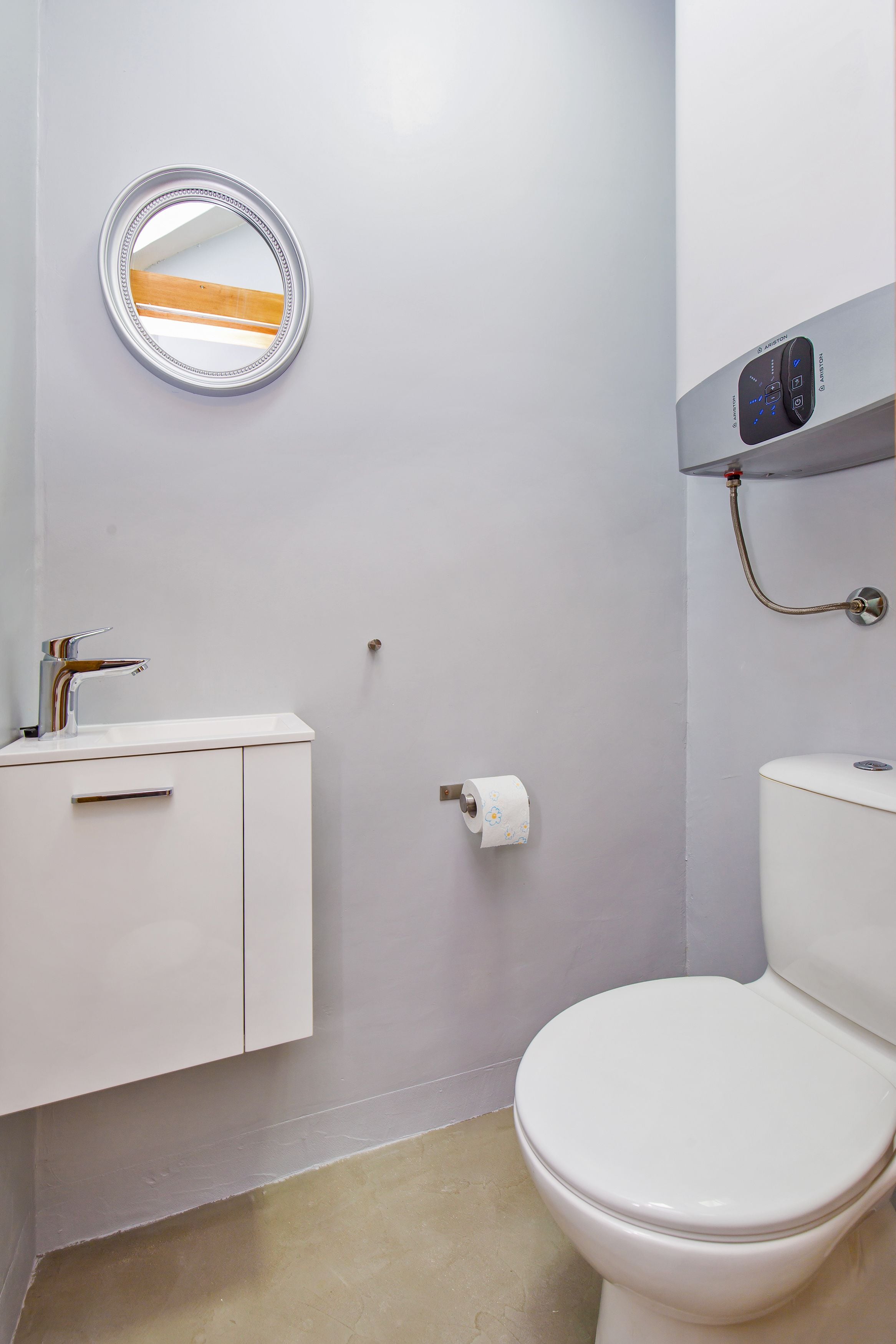 Un bagno con il water, lavandino, specchio e pannello comandi per la doccia.