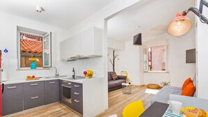 Una cocina moderna con armarios grises, un horno empotrado y una ventana con vistas a un tejado con azulejos.