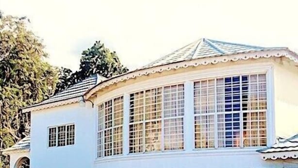 Un edificio de dos pisos con fachada curva, ventanas amplias y techo de tejas.
