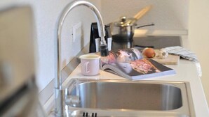 Eine Küche mit Spüle aus Edelstahl, einer weißen Arbeitsplatte und einer Zeitschrift.