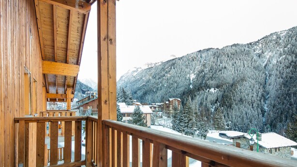 A wooden balcony with a view of a snow-covered mountain and buildings. - Proche du Centre! Appart sympa, Piscine + Sauna (Valfréjus)