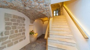 A stone staircase with a wooden handrail and a potted plant at the bottom.