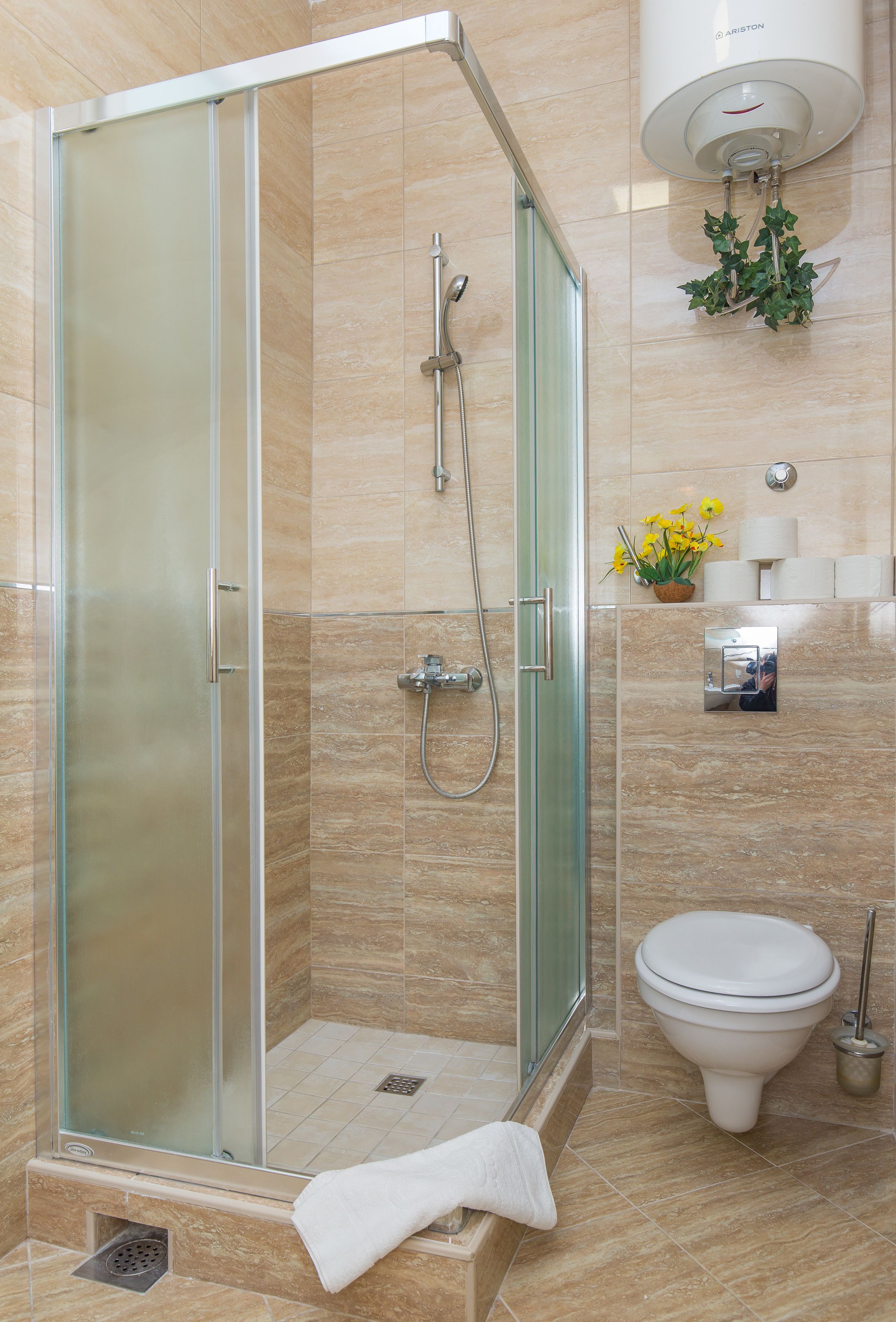Un baño moderno con ducha de vidrio, inodoro y soporte de papel higiénico en la pared.