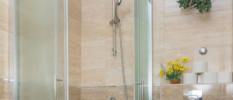 Un baño moderno con ducha de vidrio, inodoro y soporte de papel higiénico en la pared.