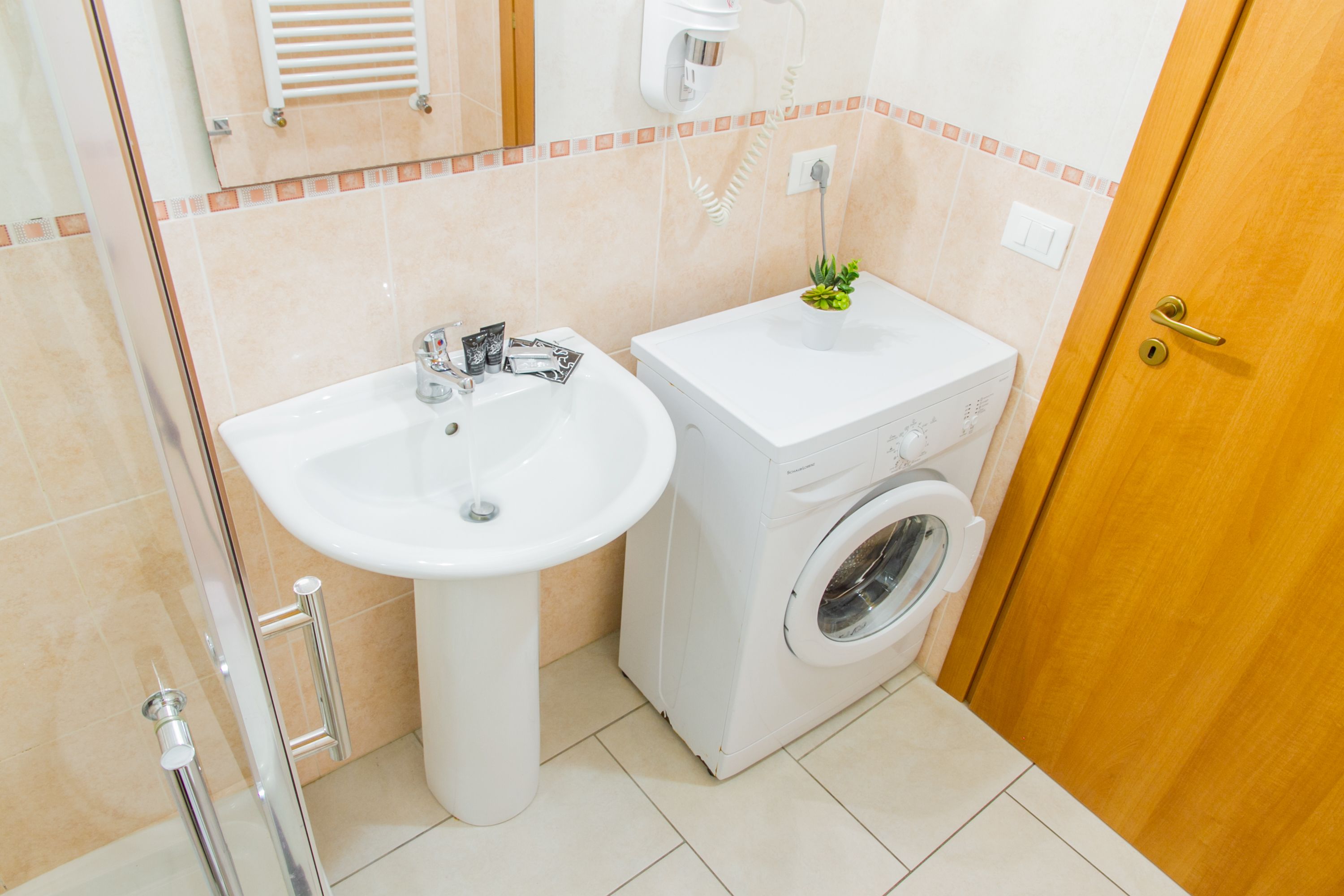 A bathroom with a sink, a washing machine, and a towel rack.
