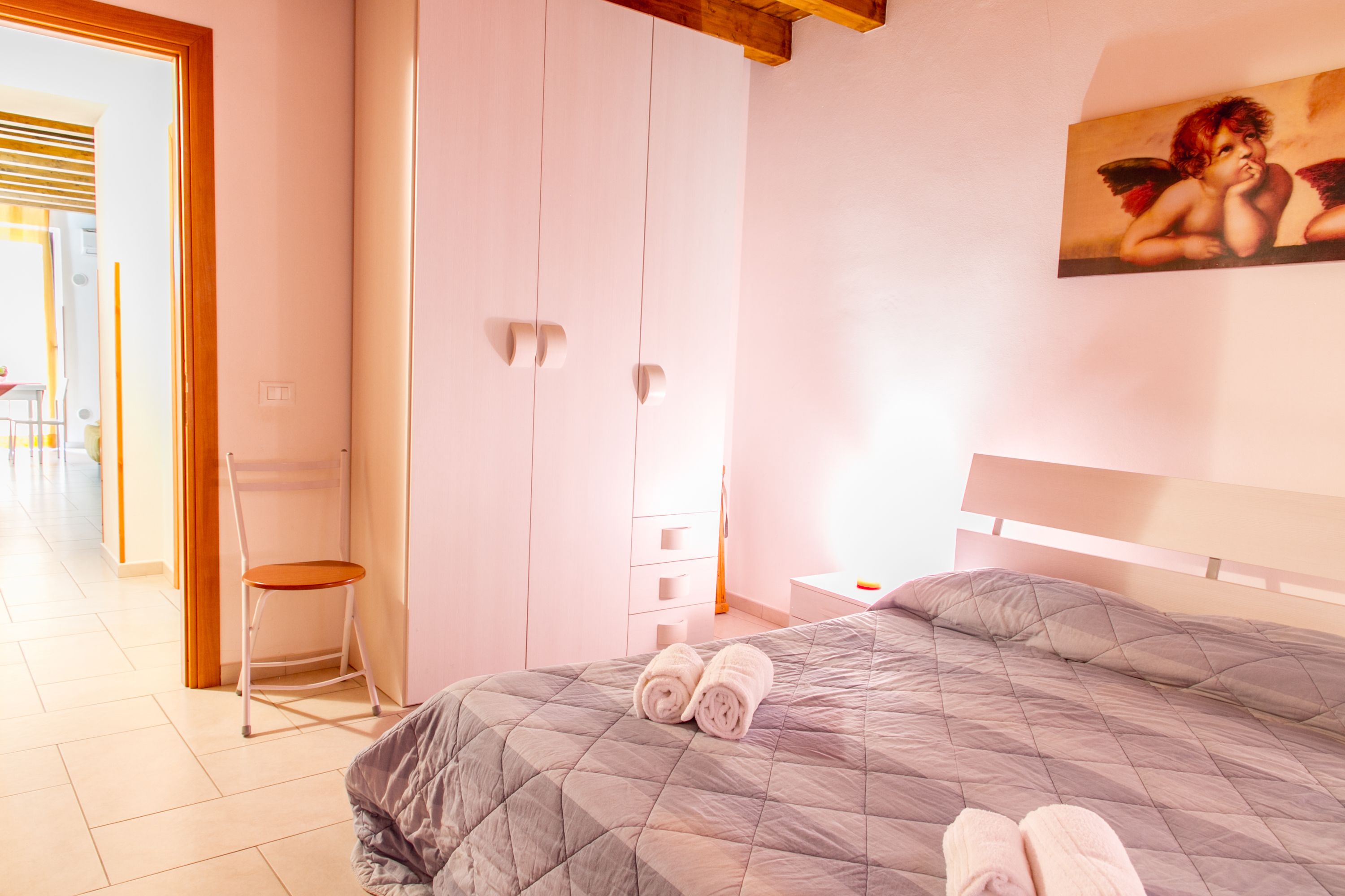 A bedroom with a bed, a chair, and a painting on the wall.