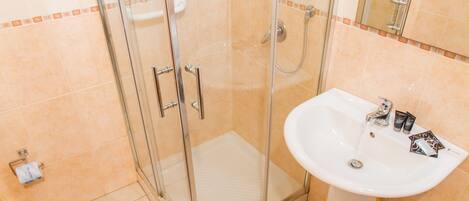 A bathroom with a glass shower enclosure, a white sink, and a toilet.
