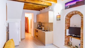 Una cocina compacta con vigas de madera, estufa integrada y un arco de ladrillo.
