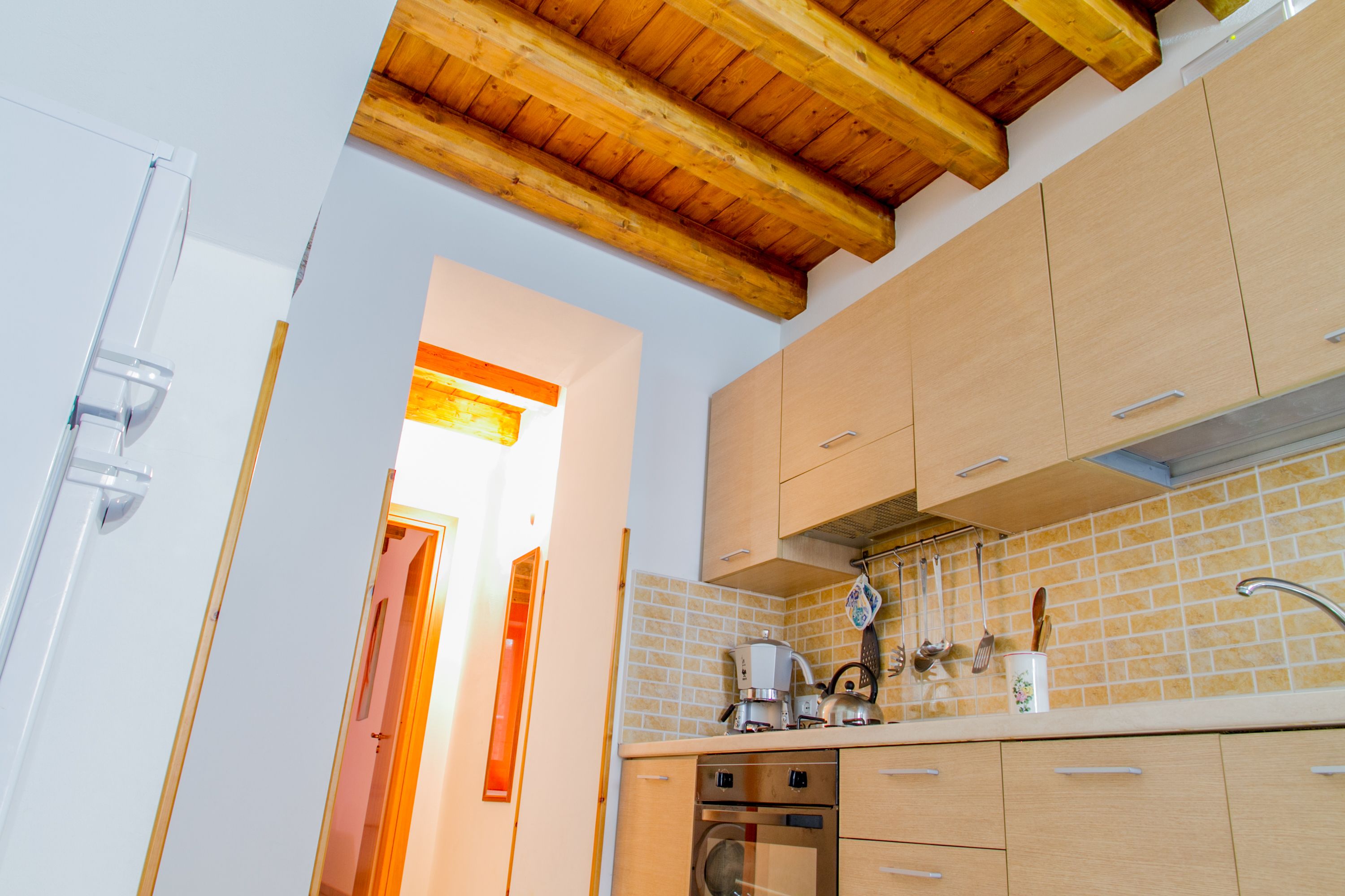 Una cocina con armarios de madera, un lavamanos de acero inoxidable y un salpicadero de azulejos.