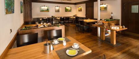Un restaurant avec des tables et des chaises en bois, un ventilateur de plafond et des lampes fixées au mur.