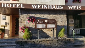 Une enseigne d’hôtel portant le nom « Hotel Weinhaus Weis » et, en dessous, un panneau affichant le menu.