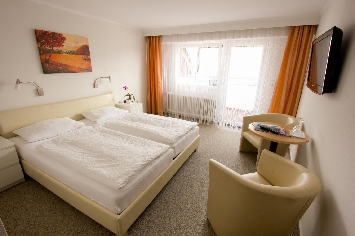 A hotel room with a large bed, a desk, a chair, and a TV.