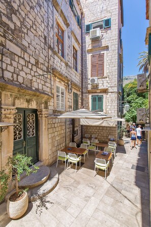 A courtyard with outdoor seating, stone buildings, and a green door. - Apartment Seagull (Dubrovnik)