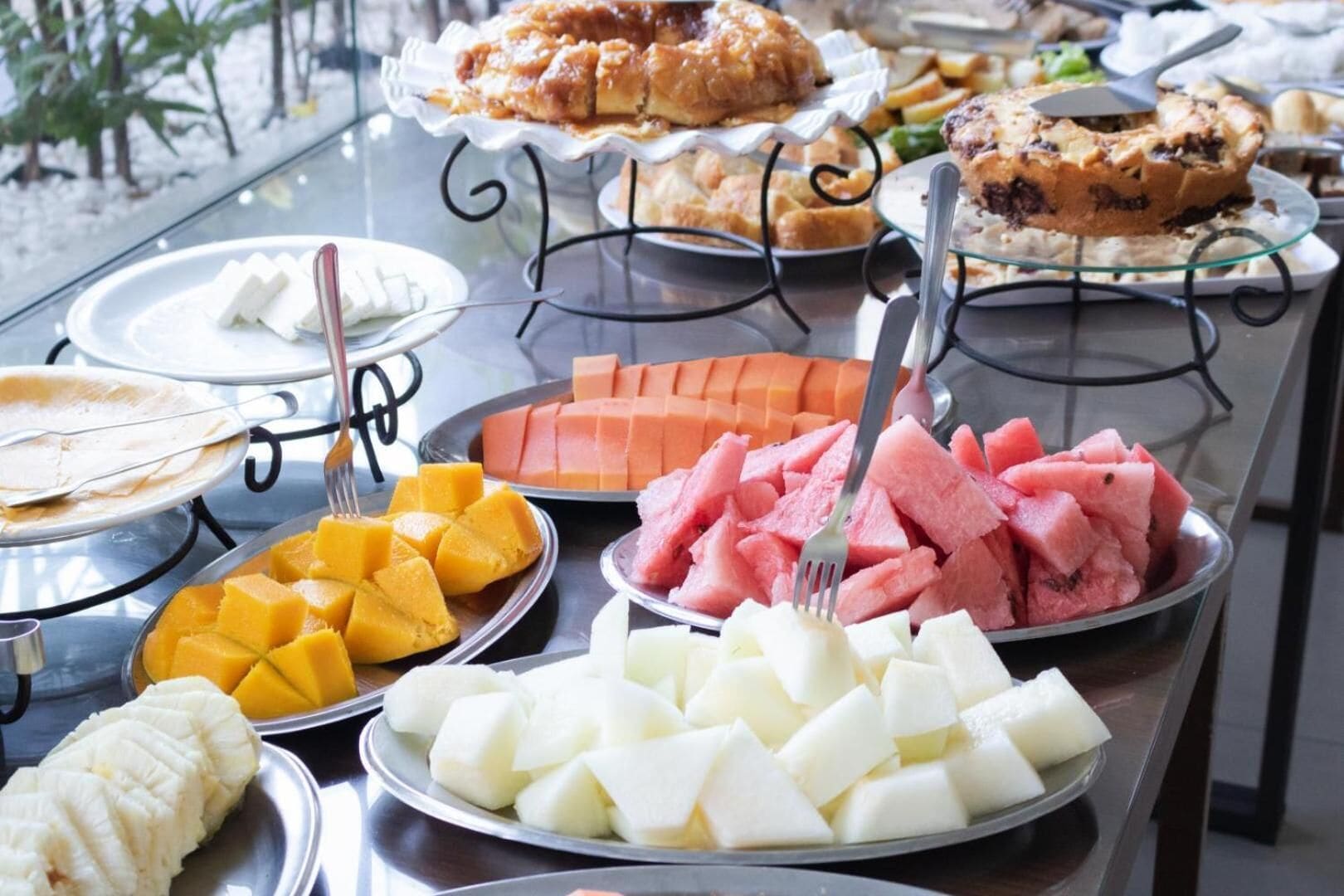 A buffet table with various fruits and desserts.