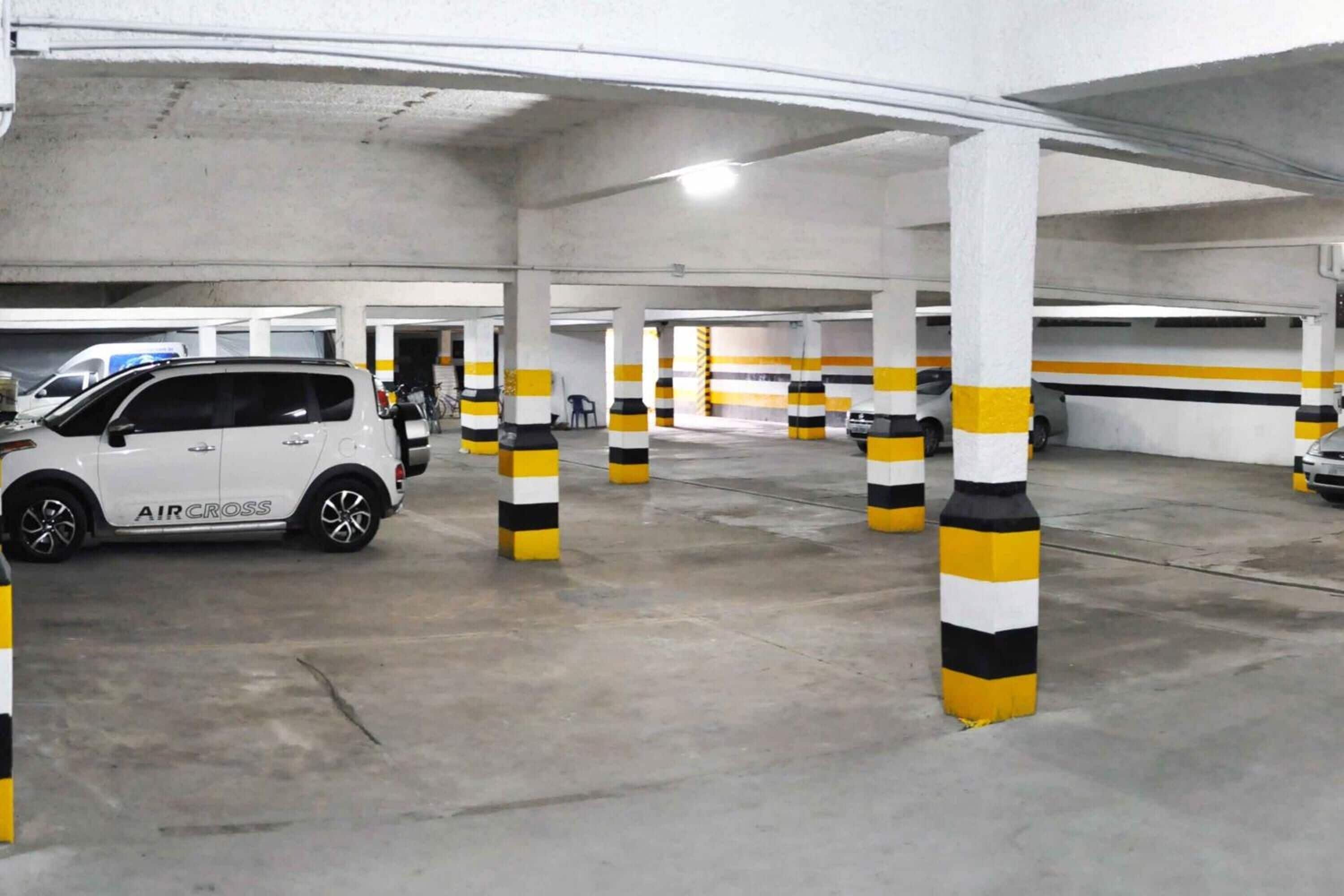 Eine Tiefgarage mit weißen Säulen und gelb-schwarz gestreiften Schutzbalken.