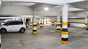 An underground parking garage with white pillars and yellow and black striped bollards. - Antonius Imperial Hotel (Santo Antonio de Jesus)