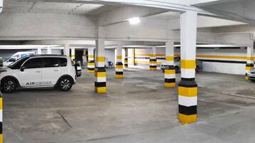 Eine Tiefgarage mit weißen Säulen und gelb-schwarz gestreiften Schutzbalken.