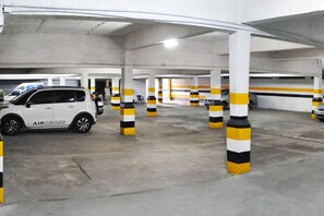 An underground parking garage with white pillars and yellow and black striped bollards. - Antonius Imperial Hotel (Santo Antonio de Jesus)