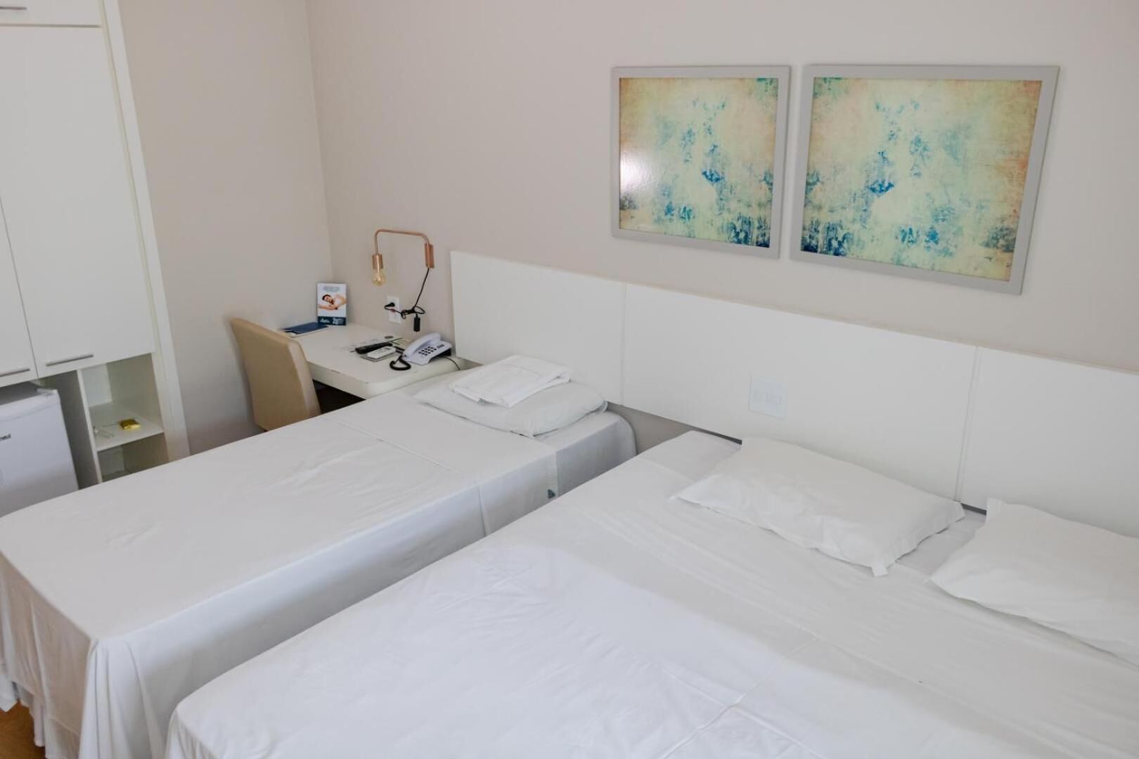 Habitació d'hotel amb dos llits individuals, una taula amb un telèfon i una cadira.
