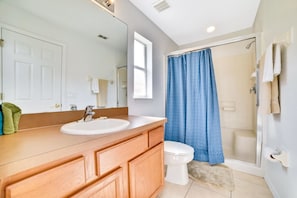 A bathroom with a wooden vanity, white sink, and a shower with a blue curtain. - 4 Br Pool Home with Spa in Aviana (Davenport)