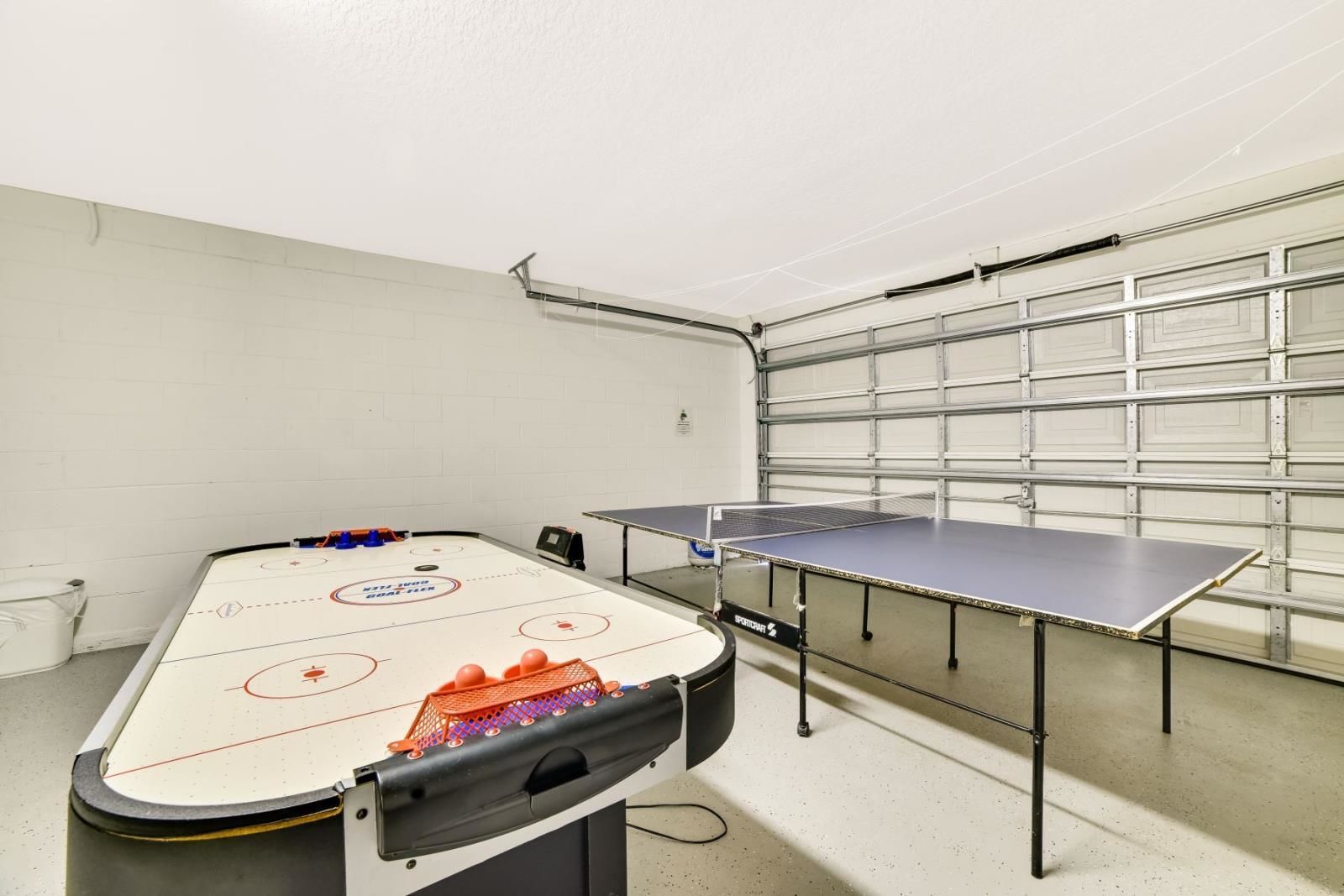 Una habitación con una mesa de hockey sobre hielo, una mesa de tenis de mesa y una puerta de garaje.