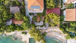 An aerial view of a coastal property with a large house, a beach, and a small boat docked near the shore. - Villa Vicko (Starigrad)