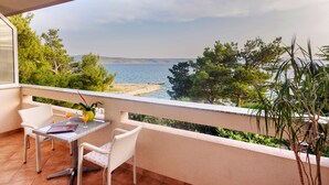 A balcony with a table and chairs, overlooking a beach and the sea. - Villa Vicko (Starigrad)
